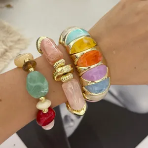 Gedetailleerd zicht op een set macaronkleurige kralenarmbanden en gouden armbanden.