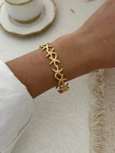 Nahaufnahme eines goldenen Seestern-Gliederarmbands am Handgelenk im Küsten-Look
