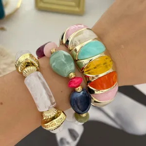 Gedetailleerde macro-weergave van macaronkleurige stenen armbandset met gouden armband