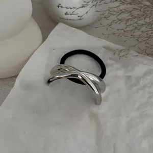 Detailaufnahme eines minimalistischen silbernen Haargummis auf weißer strukturierter Oberfläche