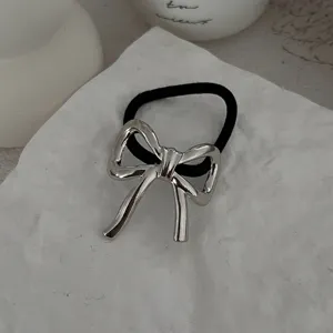 Detailaufnahme eines minimalistischen Haargummis mit silberner Metallschleife auf Stein