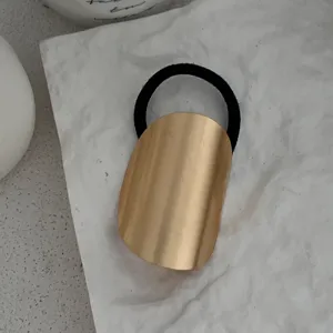Makro-Detailansicht der minimalistischen mattgoldenen Legierungsplatte am Haargummi