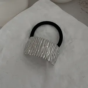 Nahaufnahme eines minimalistischen Haargummis mit einer strukturierten Silberplatte