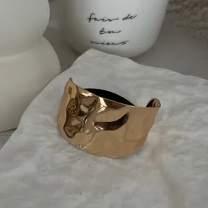Detailansicht einer unregelmäßig gehämmerten goldenen Haarspange mit schwarzem Gummiband