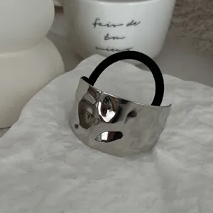 Nahaufnahme einer minimalistischen, gehämmerten silbernen Haarmanschette mit Band