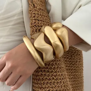 Bold matte gold wavy geometric bangles with a minimalist brushed metal finish.