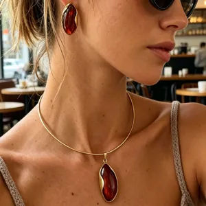Close-up detail of vintage gold amber earrings and irregular wave pendant necklace.