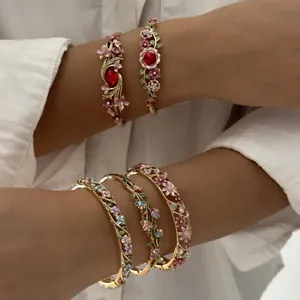 Detailed view of vintage enamel floral gold-toned bangles with red crystals on arms