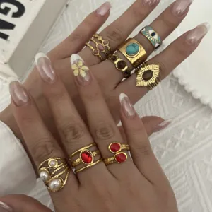 Primo piano di anelli d'oro vintage con pietre preziose colorate come turchese e occhio di tigre.