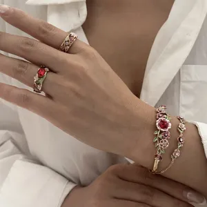 Close-up of vintage enamel flower bracelet and rings with red gemstones on model.