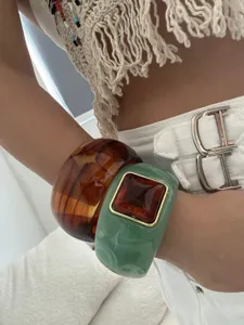 Detailed view of vintage resin bangles with amber swirl and green square accents.