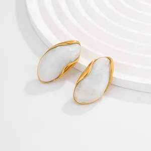 Detailed macro view of vintage gold wavy edged stud earrings with white marble resin inlay