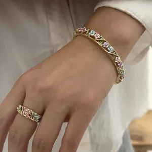 Close-up view of vintage enamel floral bangle and matching ring set on model's hand