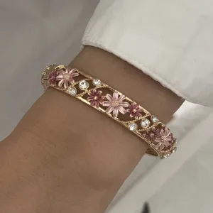 Close-up detail of a vintage floral enamel bangle with crystals worn on a wrist