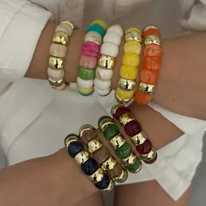 Nahaufnahme von bunten gestapelten Harzperlen-Armbändern mit goldenen Zwischenperlen