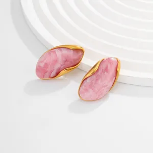 Detailed view of irregular wavy gold-edged earrings featuring pink marble resin texture
