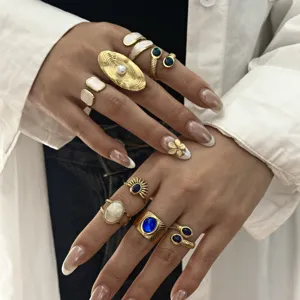 Primo piano di anelli vintage dorati regolabili con intarsi in pietra blu e bianca.