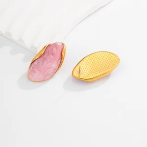 Macro detail showing front and back of irregular wavy gold earrings with pink marble inlay
