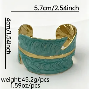 Detailweergave van turquoise emaille brede manchetarmband met gouden veerstructuur