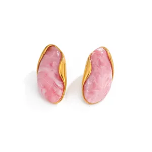 Close-up of vintage gold wavy earrings with pink marbled resin inlays for women.