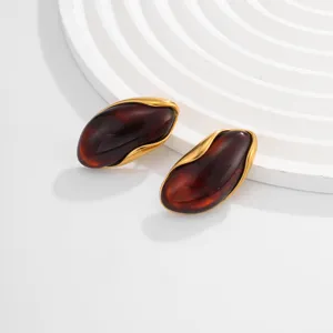Detail view of amber earrings with irregular gold wavy borders in vintage style.