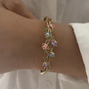 Detailed shot of a vintage enamel flower bangle with colorful vine design on a person's wrist