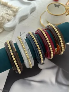 Primo piano di bracciali vintage in smalto con perle dorate su supporto in velluto.