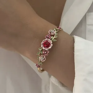 Detailed view of a vintage enamel flower bangle with red crystal and vine design