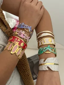 Stapel kleurrijke emaille armbanden met zeester- en kersvormige bedeltjes in goud