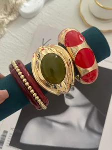 Dettaglio di bracciali vintage placcati oro con smalto rosso e pietra verde, set