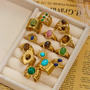 Collezione di anelli dorati vintage con malachite e occhio di tigre in un espositore.