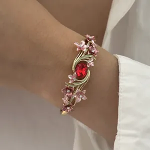 Close-up detail of a vintage enamel flower bracelet featuring a central red gemstone