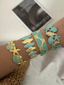 Nahaufnahme von schweren Emaille-Armbändern im Marinestil mit Muschel- und Schildkrötenmotiven