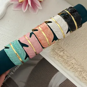 Kleurrijke brede open armbanden van email met bladtextuur op een sieradendisplay