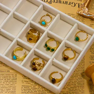 Dettaglio di vari anelli d'oro vintage con intarsi in pietra naturale in una scatola.