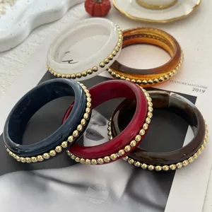 Primo piano di vari bracciali vintage in resina con eleganti bordi a perline d'oro.