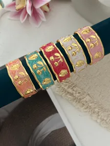 Gedetailleerde weergave van kleurrijke emaille armbanden met gouden kers- en aardbeimotieven