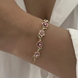 Close-up of vintage enamel floral bracelet with delicate gold vine chain design