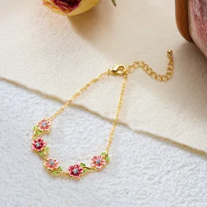 Detailed view of a vintage enamel flower bracelet with pink petals and a delicate gold chain