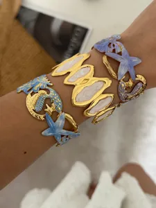 Detailopname van kleurrijke emaille armbanden met zeester- en krabmotieven in zeestijl.