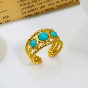 Dettaglio ravvicinato di un anello vintage dorato con tre pietre di turchese rotonde.