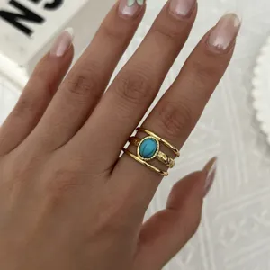 Primo piano di un anello d'oro vintage a tre bande con pietra turchese indossato al dito