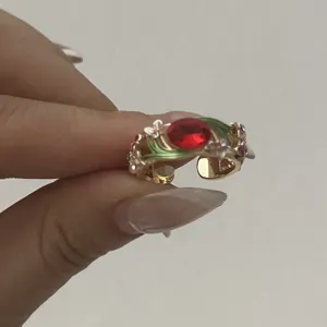 Close-up of vintage enamel floral open ring with red stone and green vine detail
