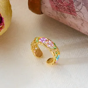 Macro detail of a vintage gold adjustable ring featuring colorful enamel flowers