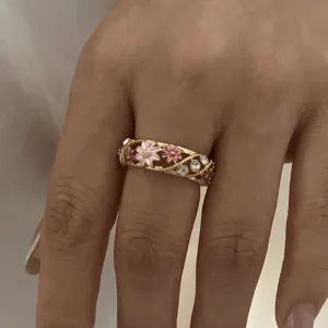Close-up view of vintage style gold-toned ring featuring pink enamel flowers and stones