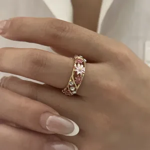 Close-up detail of a vintage golden open ring with pink enamel flowers and crystals