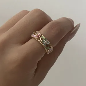 Close-up detail of a vintage gold enamel flower ring with intricate hollow vine patterns
