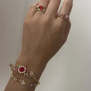 Elegant vintage enamel floral jewelry set featuring red crystal rings and a flower bangle