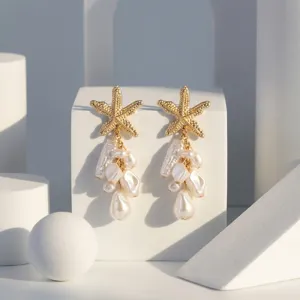 Nahaufnahme goldener Seestern-Ohrringe mit unregelmäßigen Barockperlen-Clustern