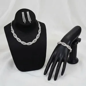 Elegante set di gioielli con strass, collana e orecchini su espositori neri.